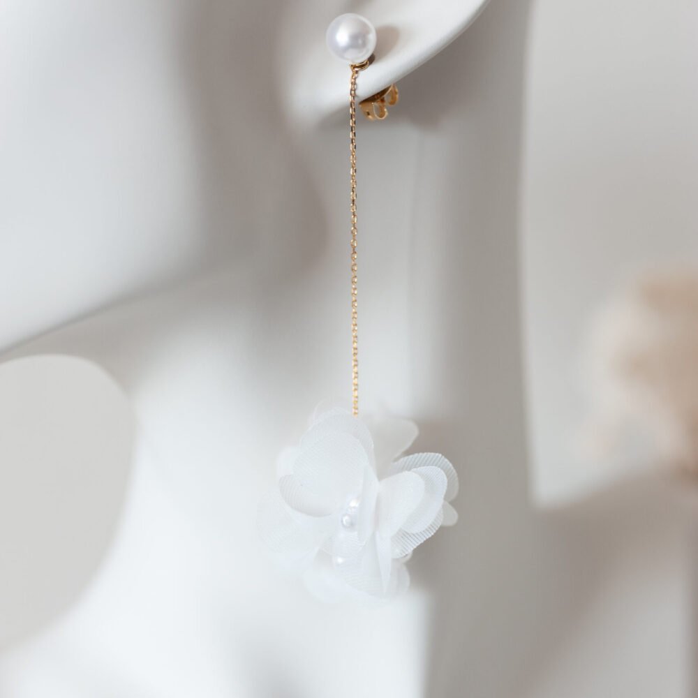 Zarte Ohrringe mit Organzablüte an Goldkette.