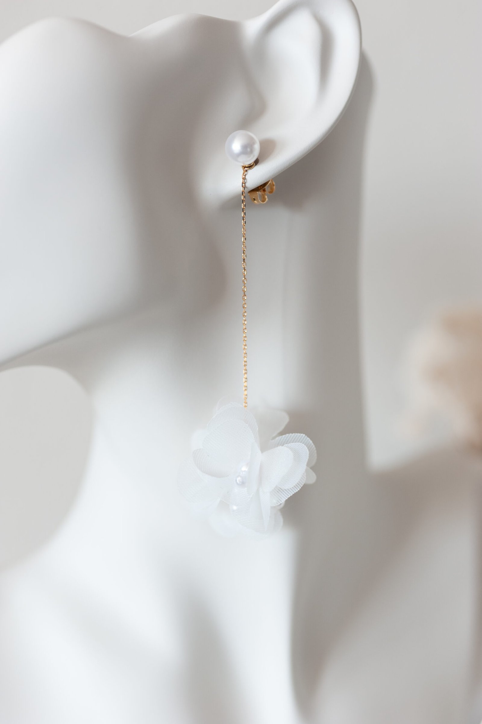 Zarte Ohrringe mit Organzablüte an Goldkette.