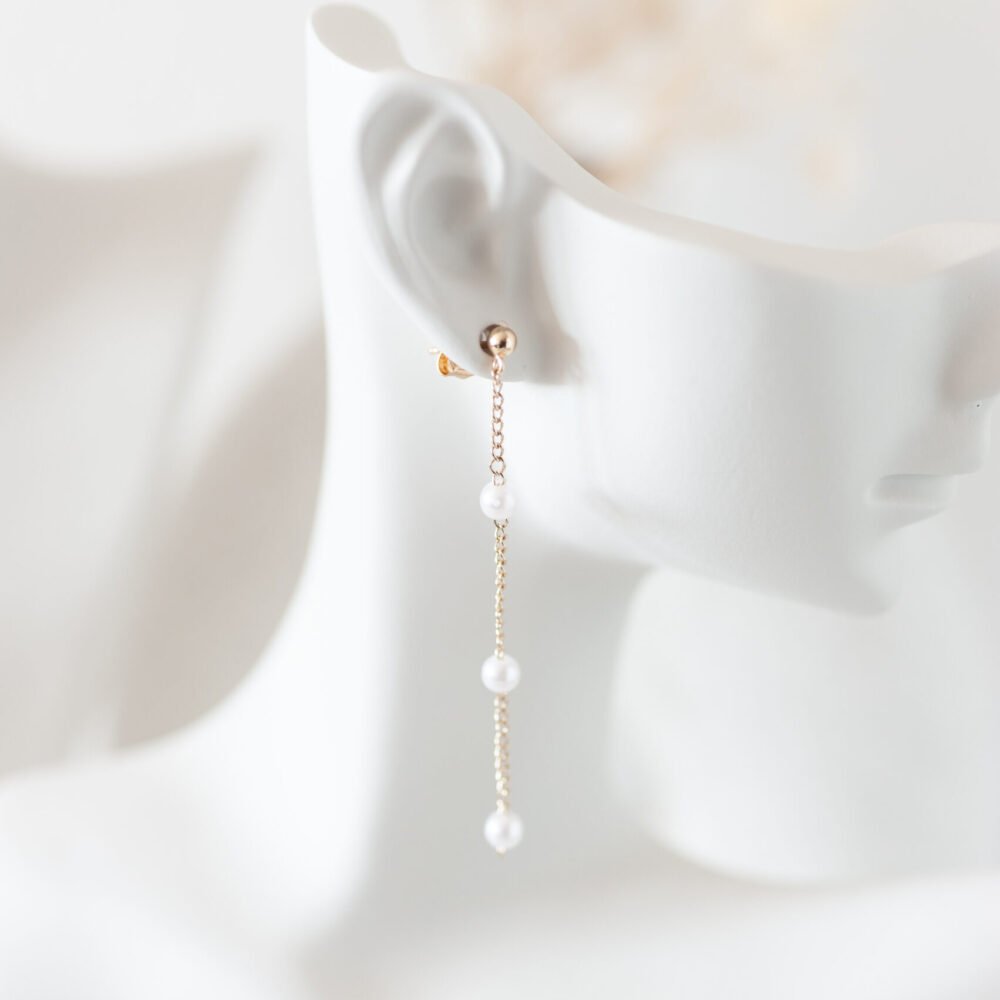 Zarte Ohrringe mit einer mit Perlen besetzten Kette als Hänger.