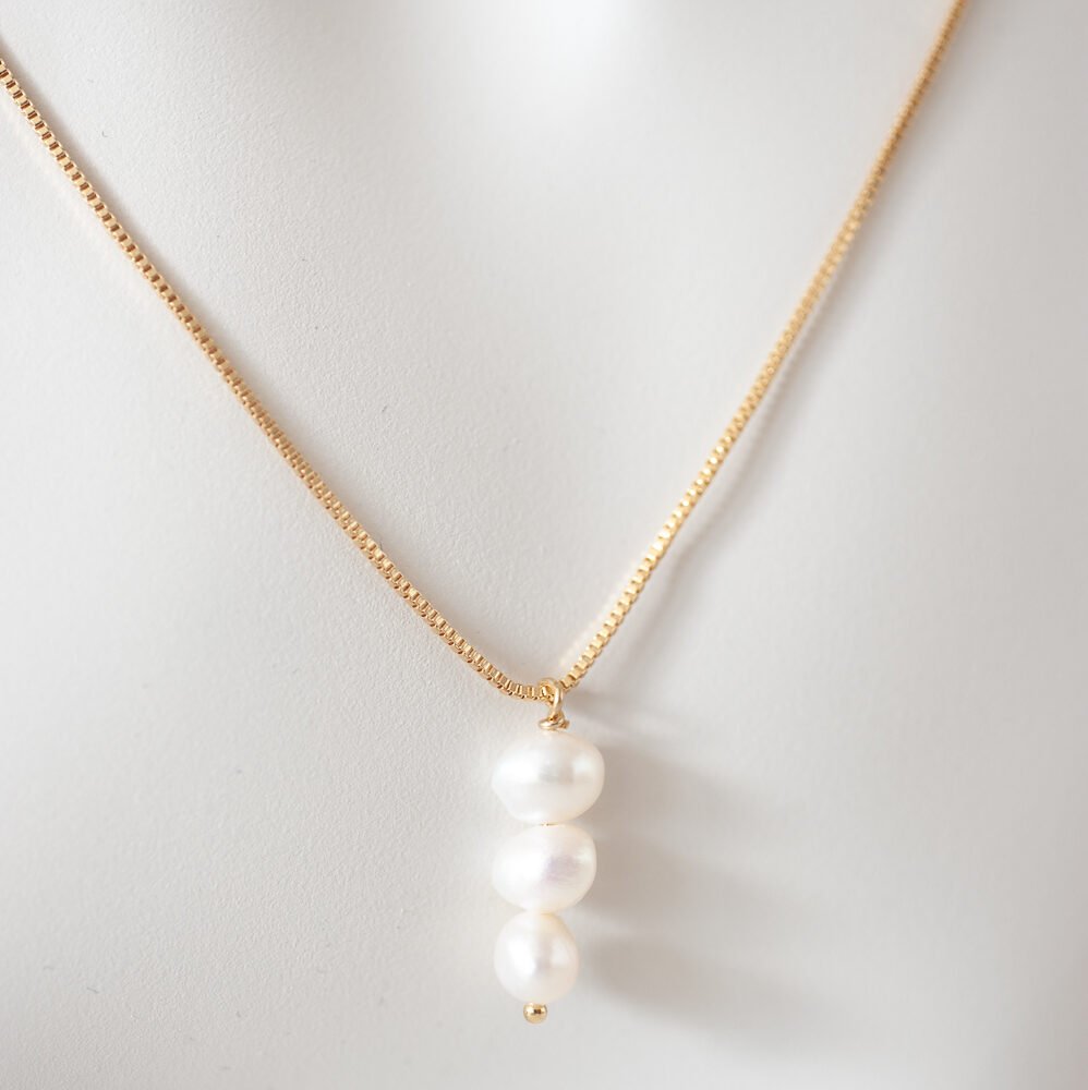 Zarte vergoldete Halskette mit drei vertikalen Perlen als Anhänger.