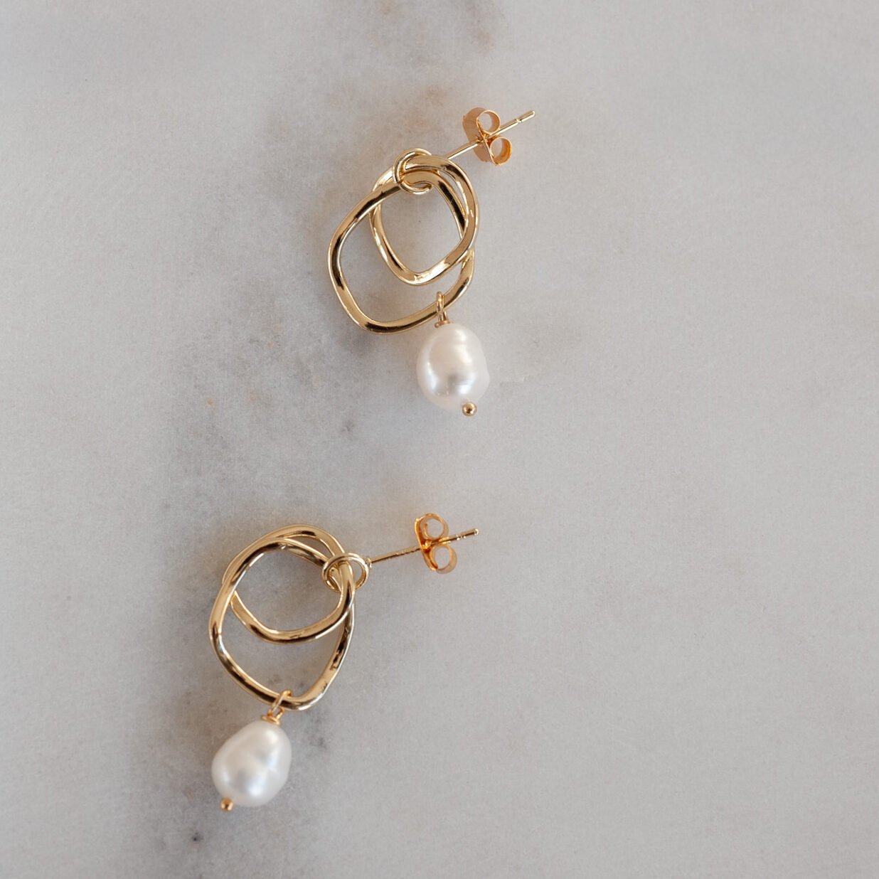 Goldohrring in organischer Form mit Süßwasserperle.